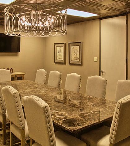 A large conference room with white chairs and marble table.