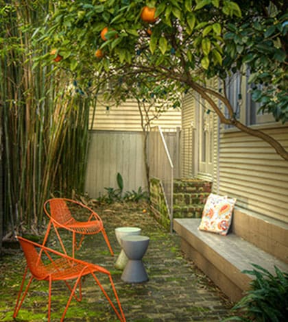 A small garden with orange chairs and a bench.