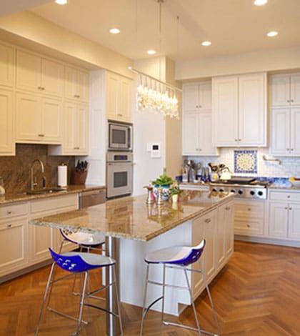 A kitchen with white cabinets and blue chairs.