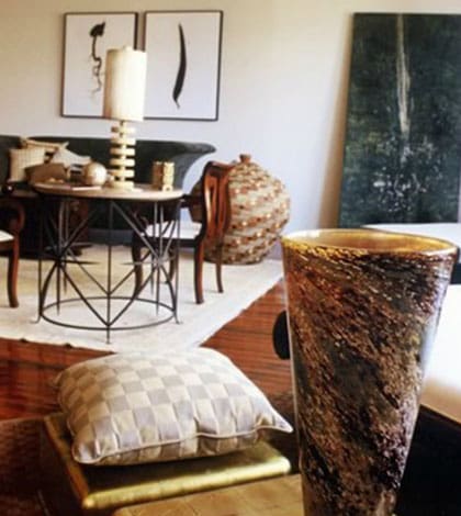 A living room with a table and chairs, a vase and a candle.