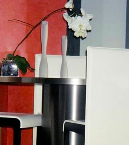 A white table with two chairs and a vase of flowers.